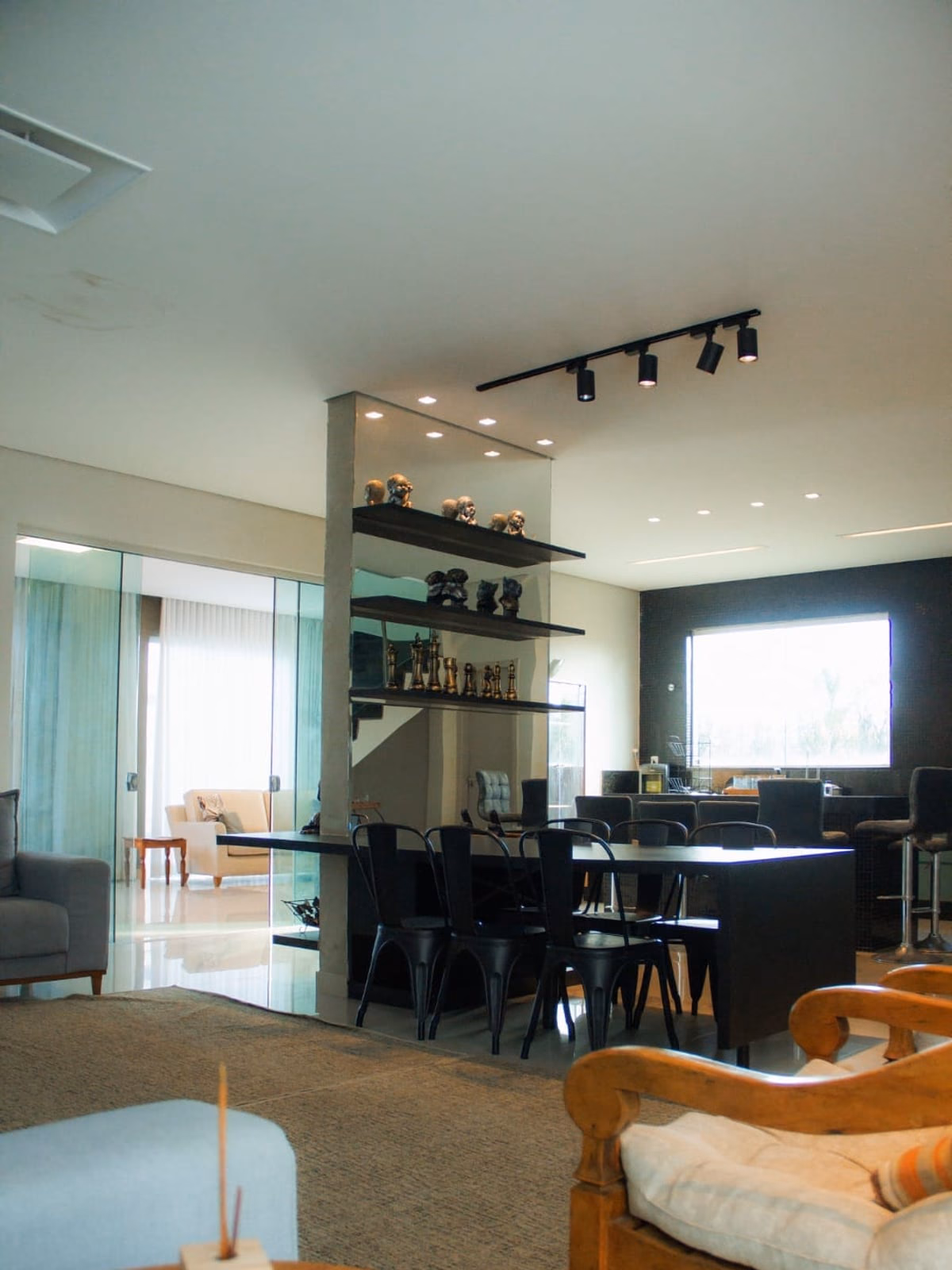 Sala de estar integrada à sala de jantar, com escada de vidro