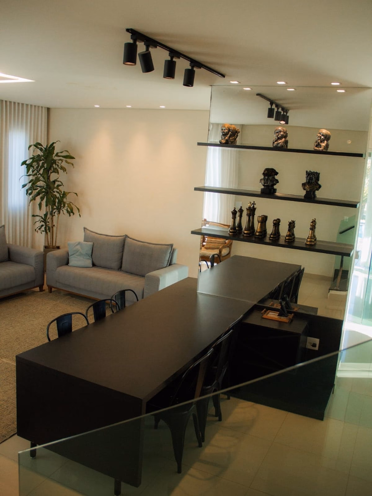 Sala de estar com sofás cinza e mezanino decorado ao fundo