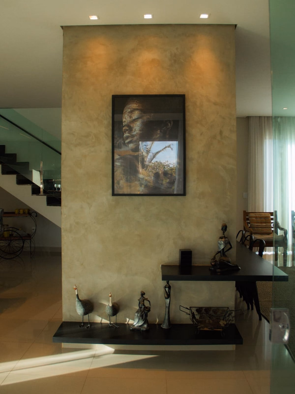 Hall interno com coluna decorativa, quadro e aparador