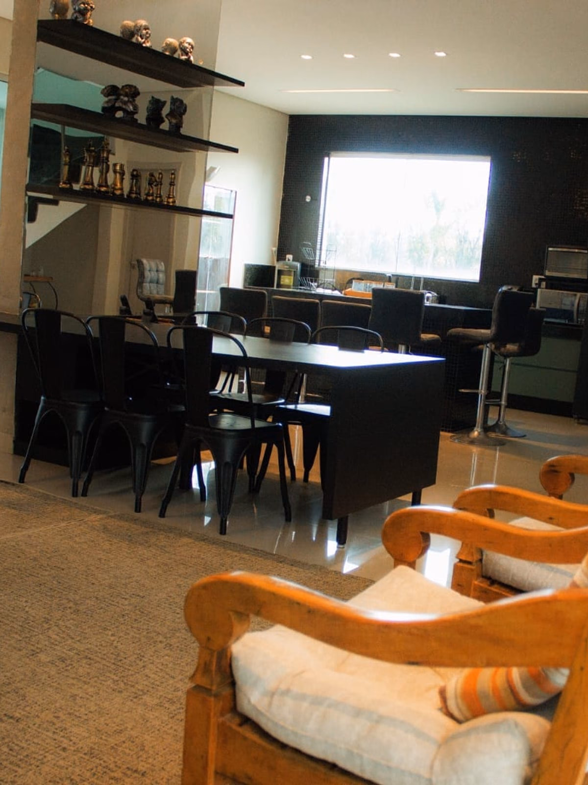 Sala de jantar com mesa preta, cadeiras pretas e cozinha ao fundo