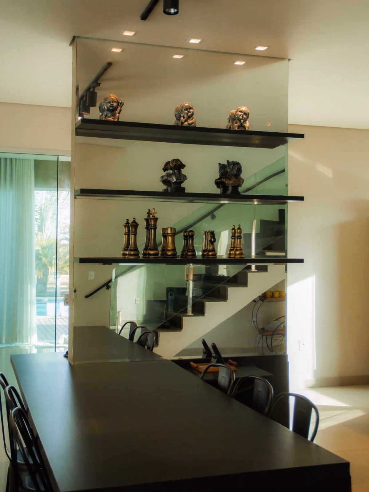 Mezanino com prateleiras de vidro decoradas sobre mesa preta comprida
