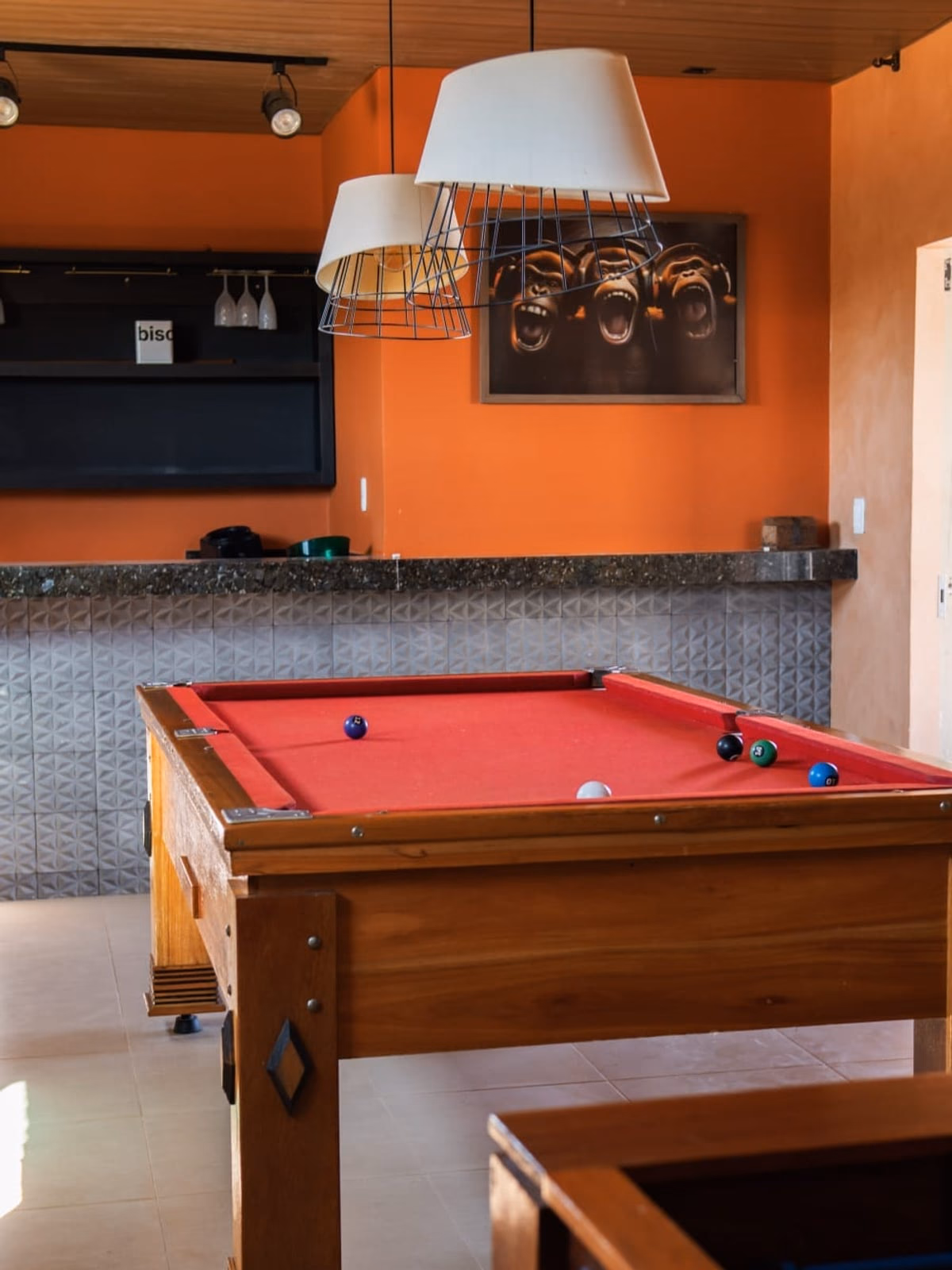 Mesa de sinuca em primeiro plano, bar ao fundo