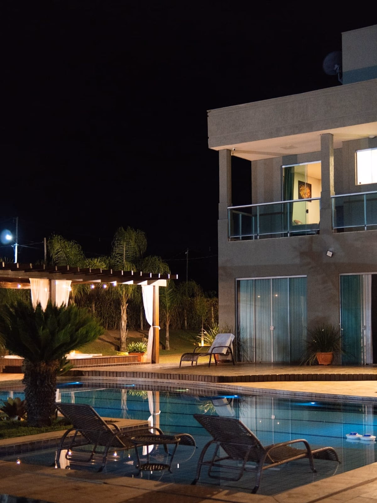 Espreguiçadeiras à beira da piscina, à noite
