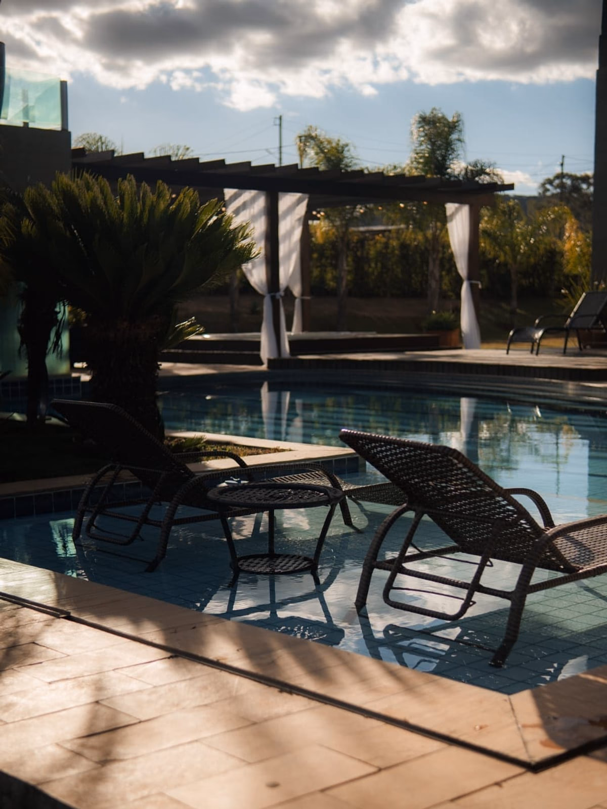 Espreguiçadeiras à beira da piscina, à sombra