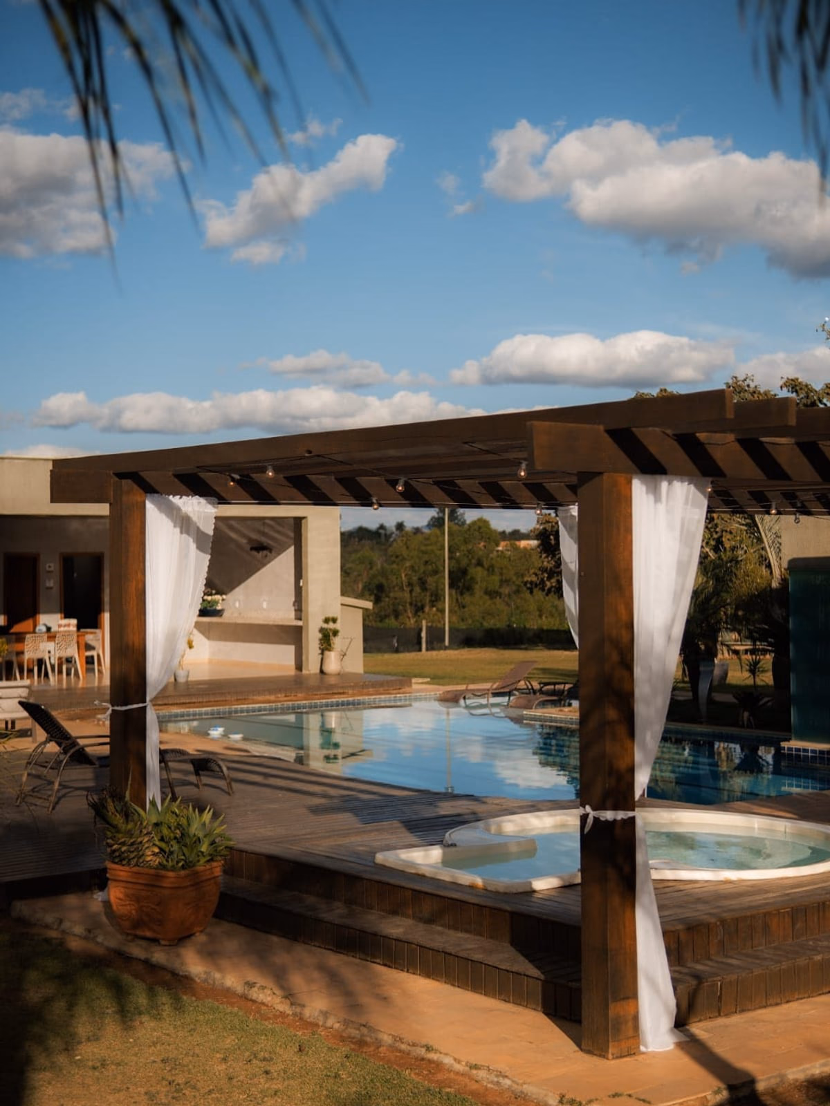 Vista ampla da piscina e hidromassagem sob o pergolado, dia claro