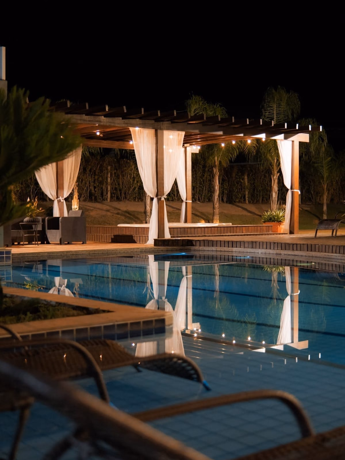 Piscina e hidromassagem à noite, luzes do pergolado acesas