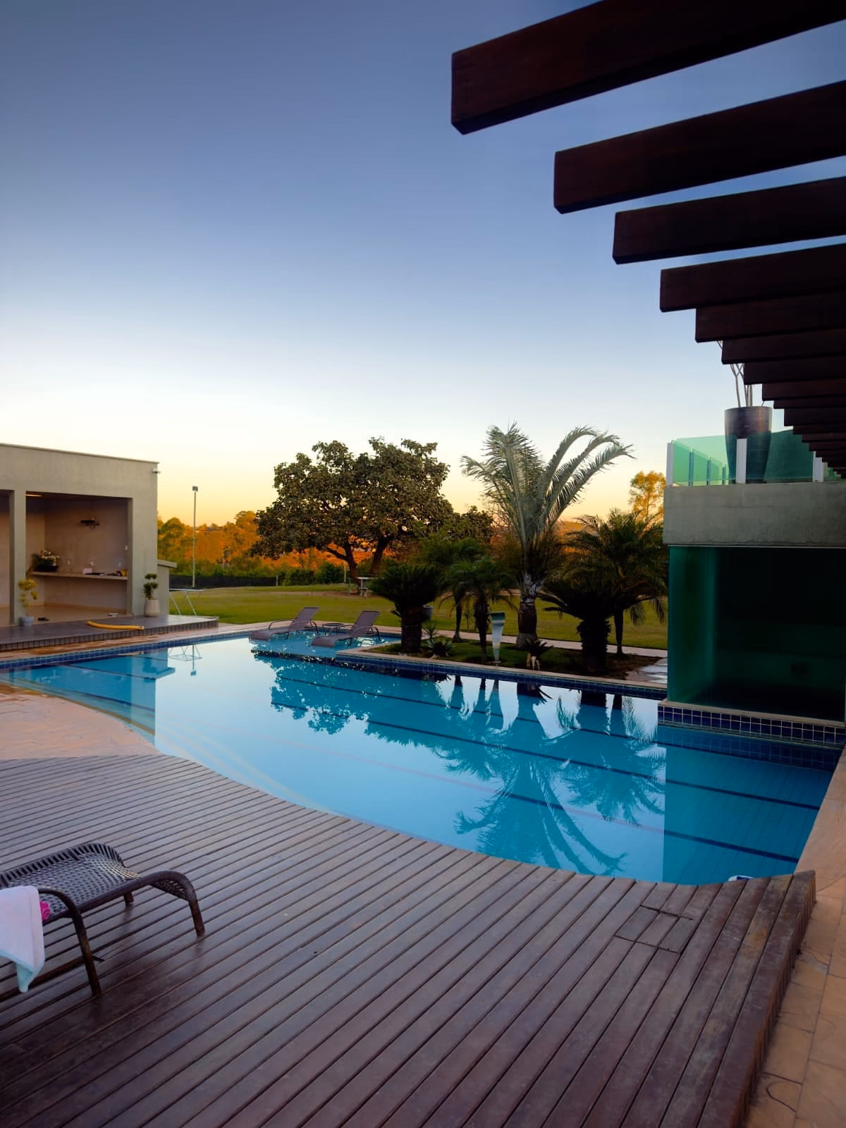 Panorama noturno da piscina entre palmeiras
