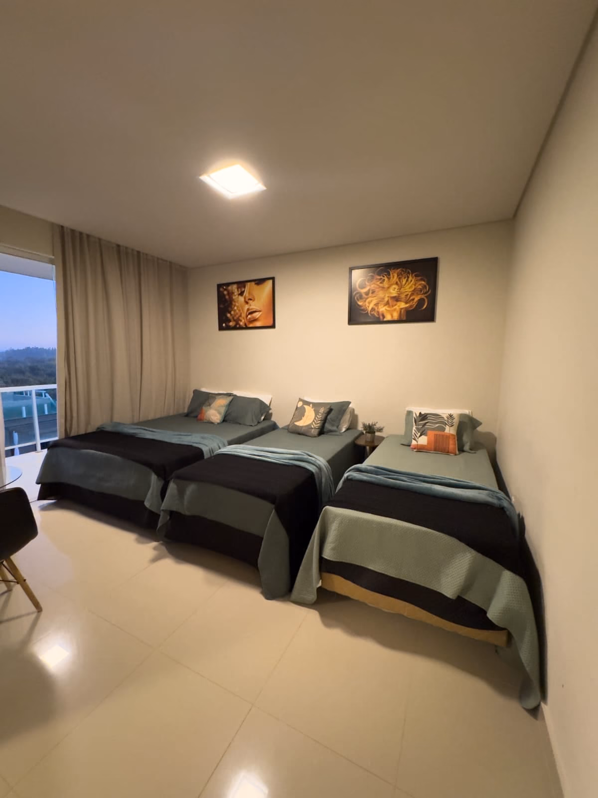 Quarto com camas de solteiro em fileira e quadros na parede