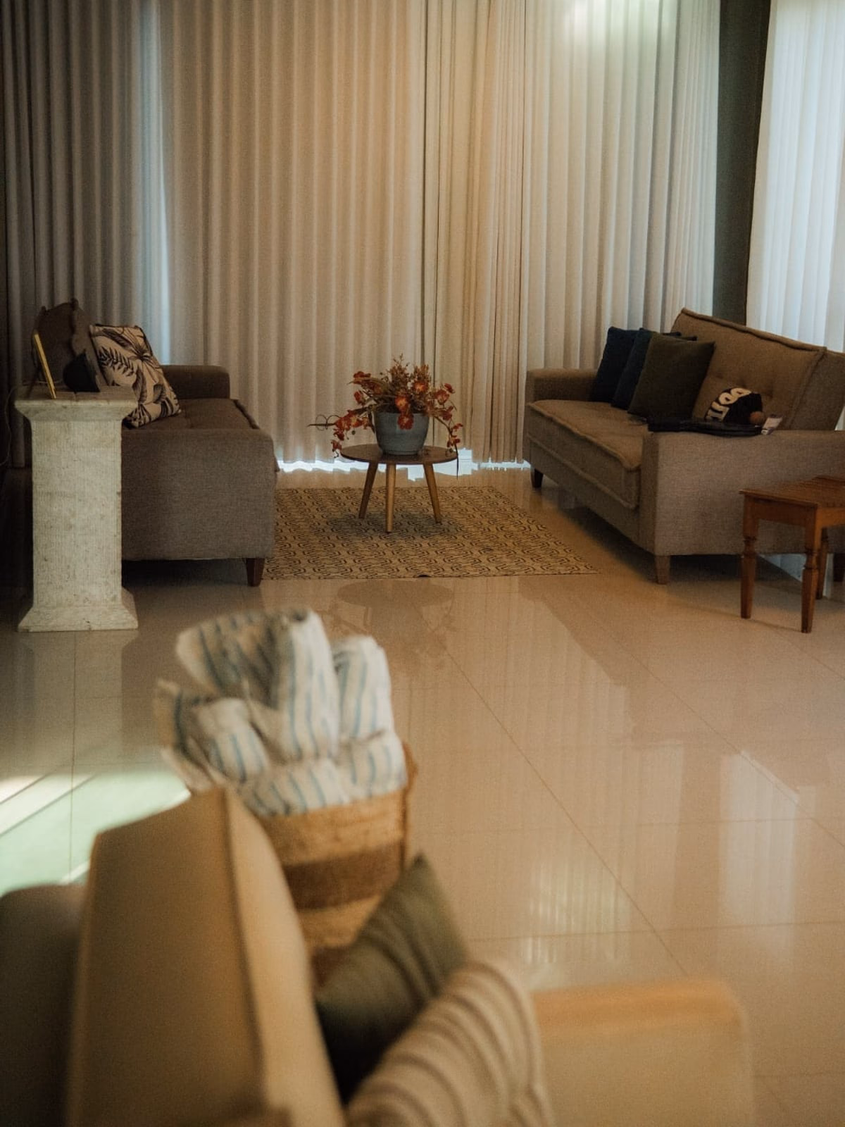 Sala de estar com dois sofás claros e cortinas longas