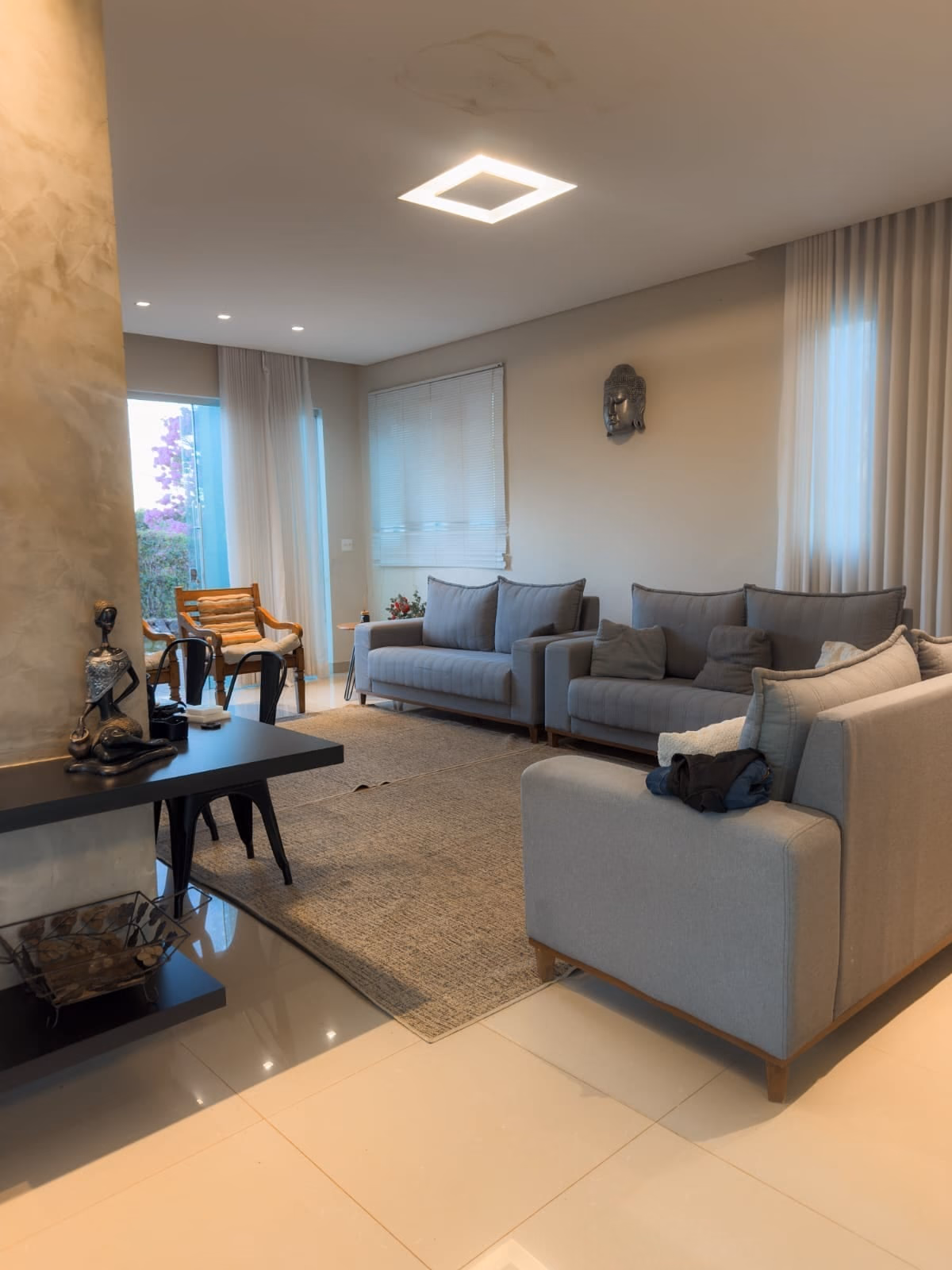 Sala de estar com sofás cinza, tapete e estante de vidro decorada